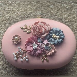 Pink clutch with floral details. Shoulder strap included